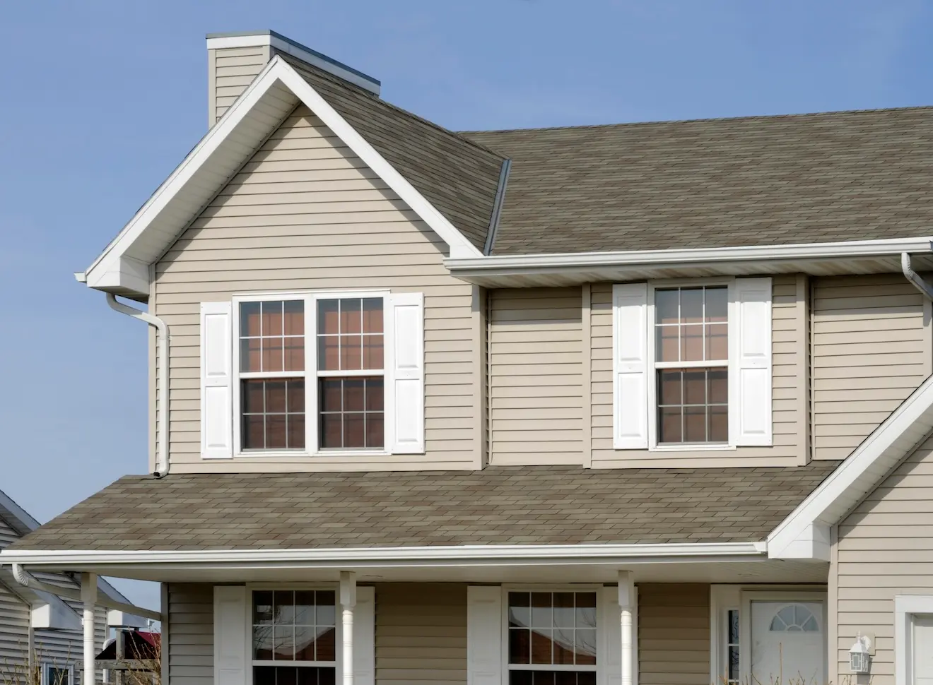 Two-story suburban home with beige siding, white trim, and large residential glass windows